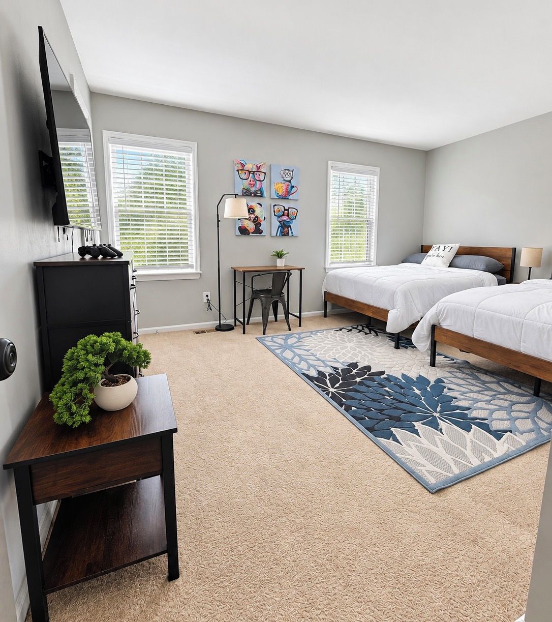 A bedroom with two beds, a desk, a TV, and artwork on the wall.