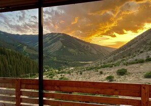 Un banco de madera con vistas a un paisaje montañoso y un atardecer.