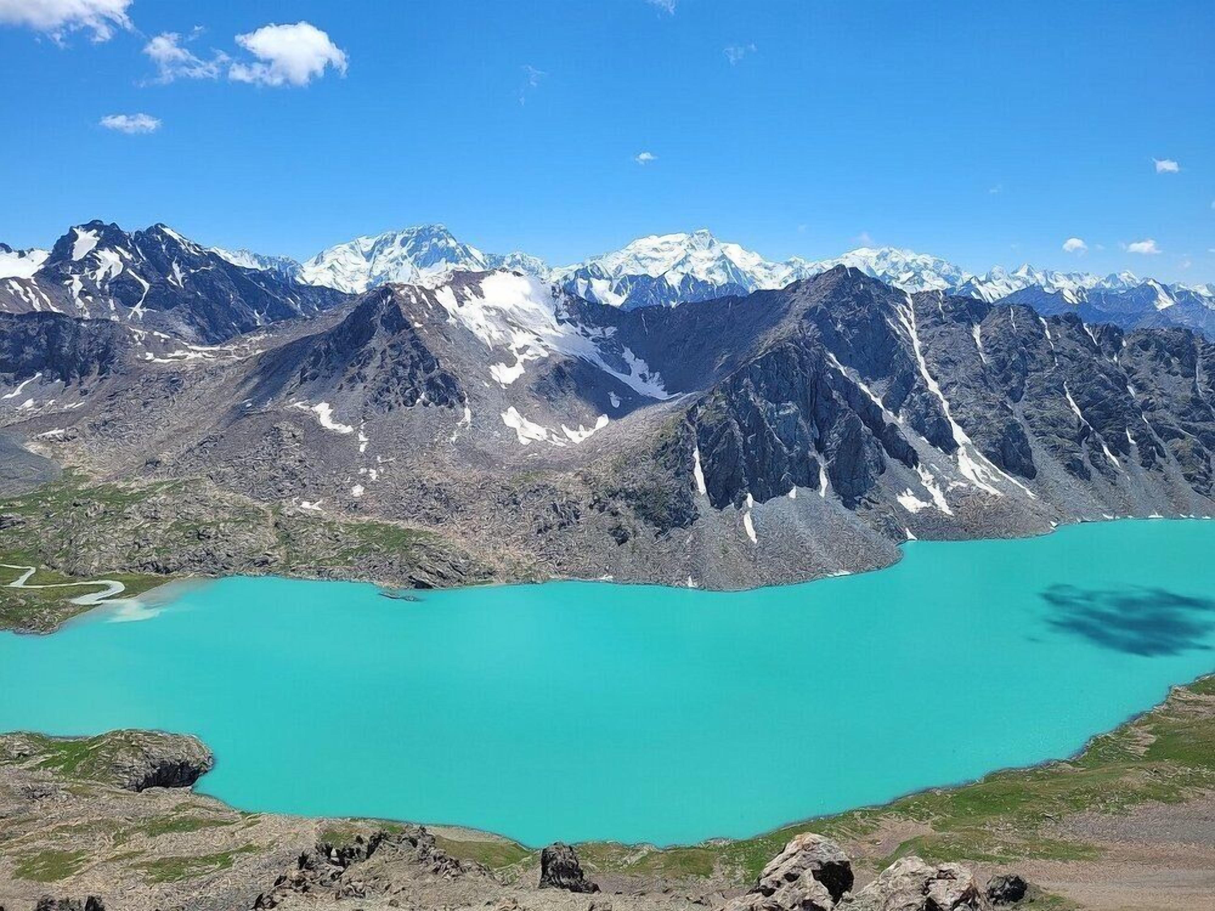 A mountain landscape with a turquoise lake and snow-capped peaks.