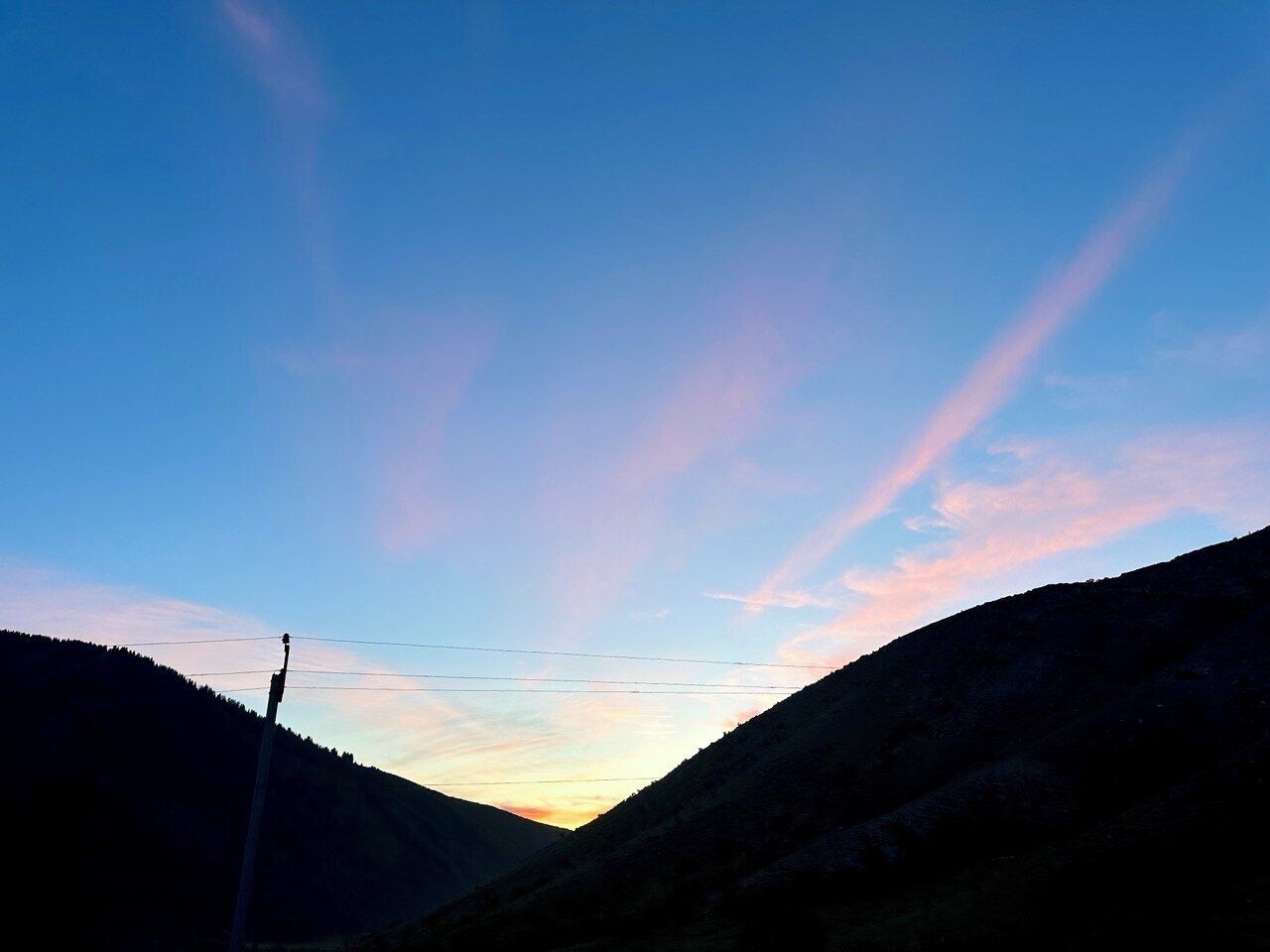 A mountainous landscape with a clear sky and power lines.