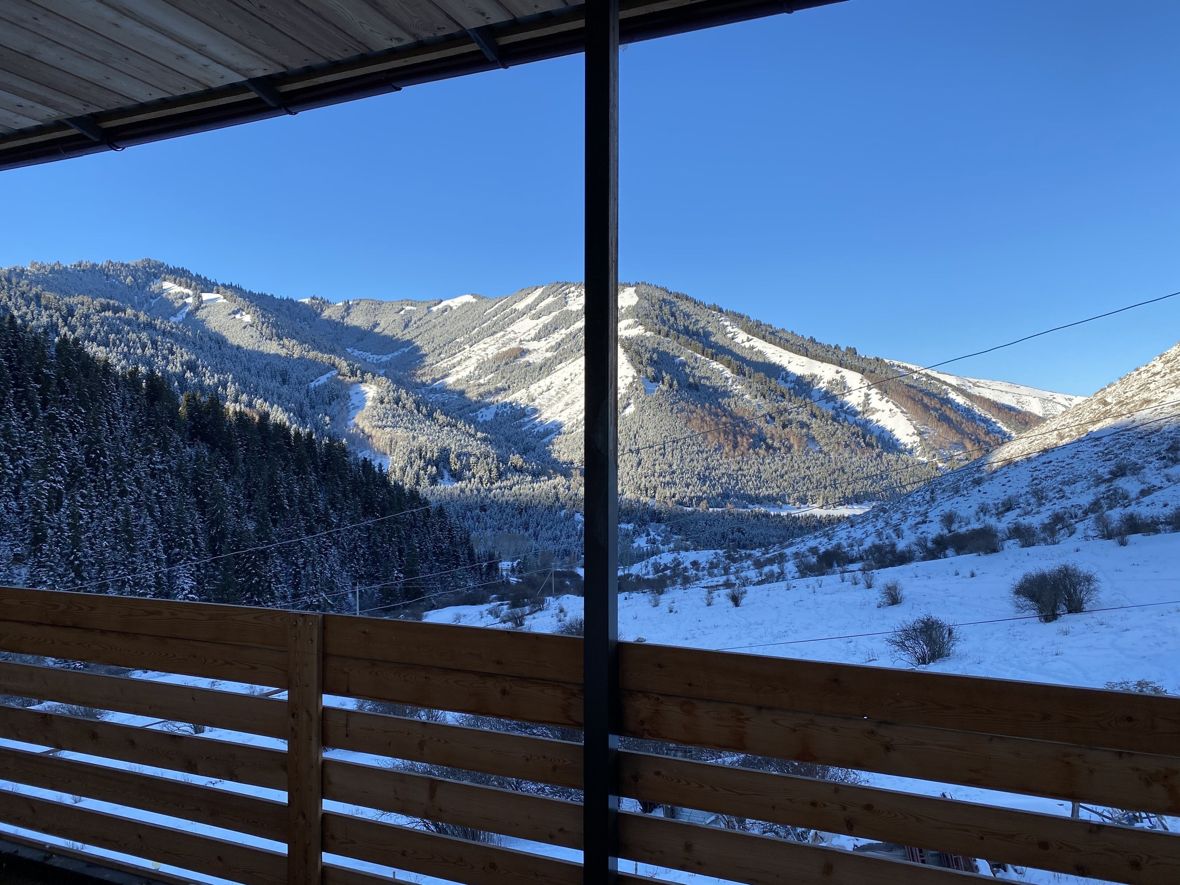 A wooden bench overlooking a snow-covered mountain landscape.