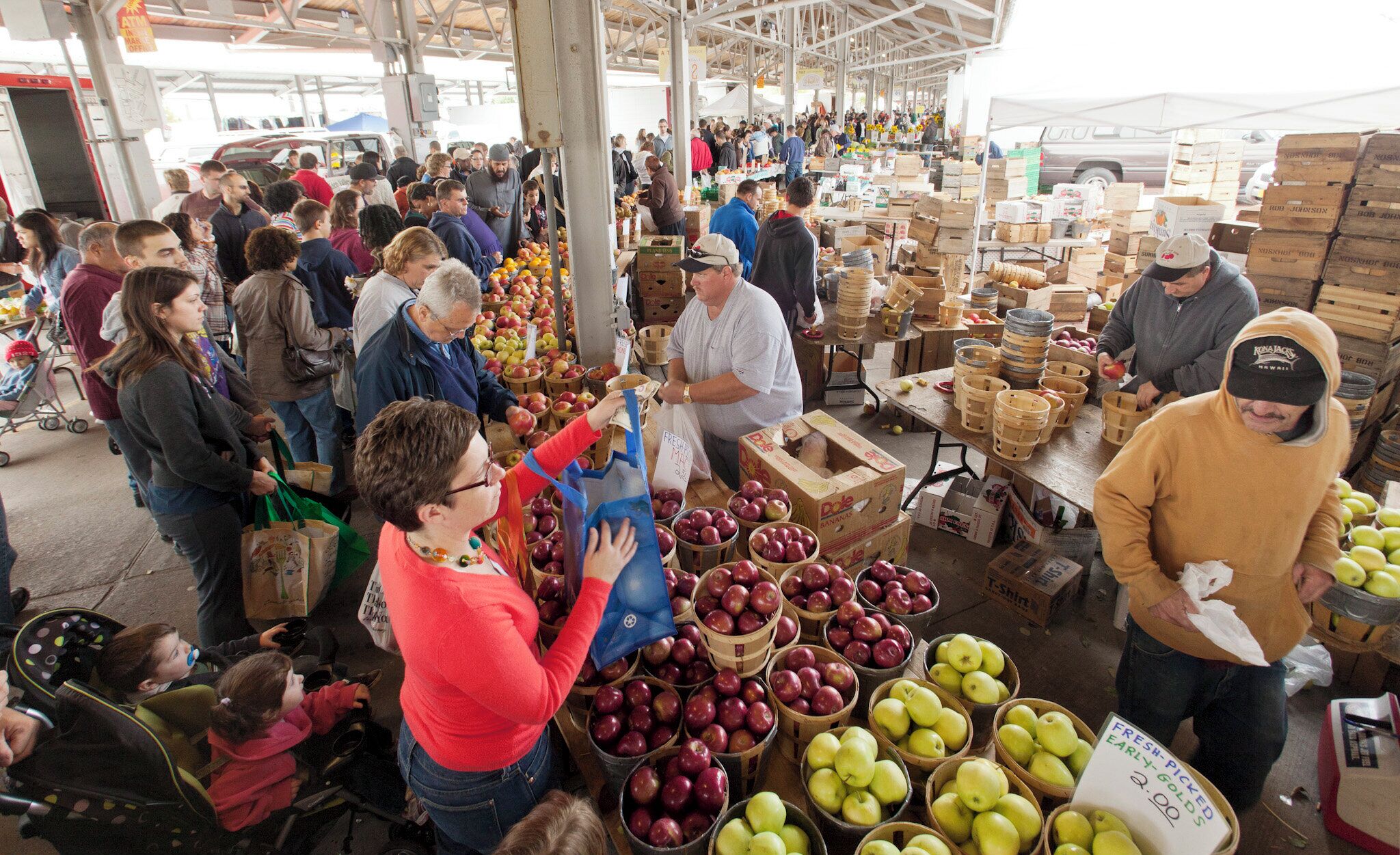 A busy outdoor market with various stalls selling fruits and vegetables.