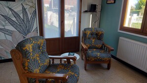 A room with two wooden chairs with floral upholstery, a white radiator, and a window with a view of buildings. - Spacious family home close to the sea (Cayeux-sur-Mer)