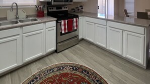 A modern kitchen with white cabinets, a stainless steel stove, and a microwave.