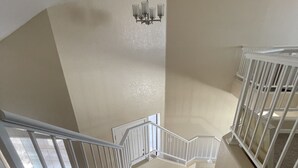 A carpeted staircase with white railings and a chandelier.