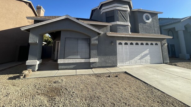 A residential house with a garage, a driveway, and a well-maintained lawn.