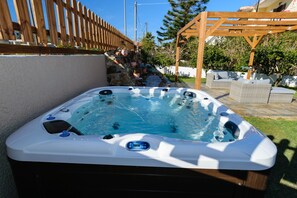 A hot tub with a digital control panel, surrounded by a wooden pergola and outdoor furniture. - Villa Albion (Platanias)