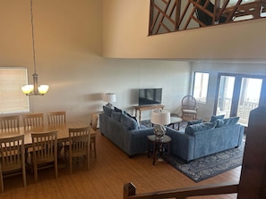 A living room with a dining area, a sofa set, a TV, and a staircase.