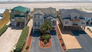 Una propiedad frente a la playa con varias construcciones, incluyendo una casa central con balcón y una estructura más pequeña a la izquierda.