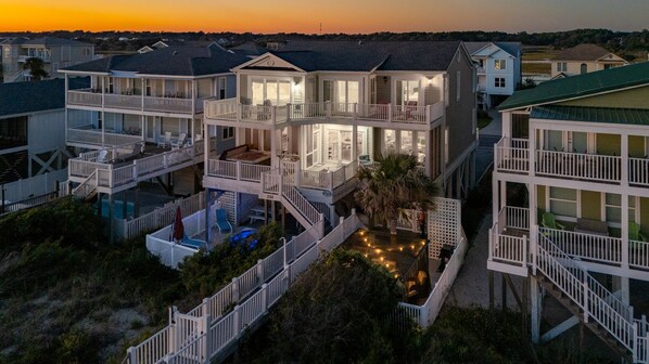 Una propiedad frente a la playa con varios pisos, balcones, piscina y un interior bien iluminado.
