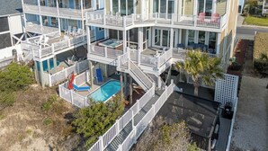 Una casa de varios pisos con piscina, balcones y un patio cubierto.