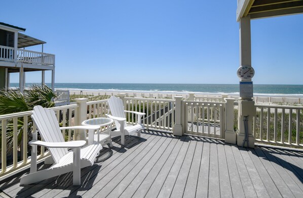 Enjoy the ocean view from this deck with Adirondack chairs and a table.