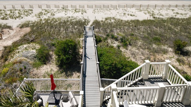 Una terraza de madera que da a una playa, con vista al océano.