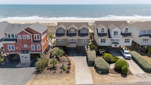 Un quartier résidentiel situé en bord de mer, avec des maisons, une plage de sable et l’océan.