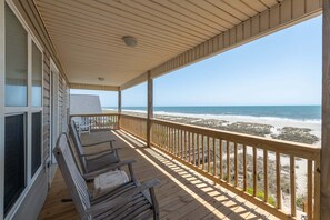 A wooden deck with a railing overlooking a beach. - Hobbs Realty - “Southern Exposure” | Spectacular Oceanfront Home w/ 2 Living Areas & Open Floor Plan (Holden Beach)
