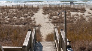 Une promenade en bois mène à une plage, et un panneau indique la présence de dunes et une amende de 500 dollars en cas de non-respect des règles.