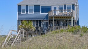 A two-story house with a balcony on the second floor. - Hobbs Realty - Oceanfront home w/Private Pool, Luggage Lift, and Hot Tub (Holden Beach)