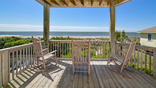 A wooden deck with two rocking chairs overlooking a beach. - Hobbs Realty - Oceanfront home w/Private Pool, Luggage Lift, and Hot Tub (Holden Beach)