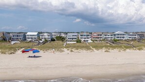 A beachside hotel with multiple buildings, a sandy beach, and a view of the ocean.