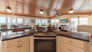 A spacious kitchen with a central island, large windows, and a view of the ocean.