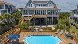 A large house with a swimming pool, wooden deck, and a covered patio area. - Hobbs Realty - "That's It II" an amazing oceanfront home with lovely views, pool, and an elevator. (Holden Beach)