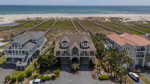 A beachfront property with multiple buildings, a beach, and a boardwalk. - Hobbs Realty - "That's It II" an amazing oceanfront home with lovely views, pool, and an elevator. (Holden Beach)