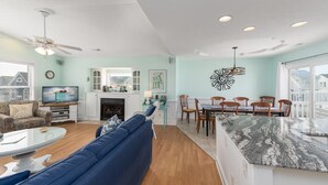 A spacious living room with a blue sofa, a dining area with a marble island, and a fireplace.