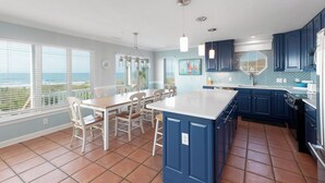 A kitchen with a large island, blue cabinets, and a view of the ocean. - Hobbs Realty - Oceanfront Dog Friendly w/Private Pool & EV Charger (Holden Beach)
