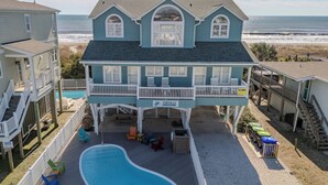 A two-story house with a pool, a balcony, and a view of the beach. - Hobbs Realty - Oceanfront Dog Friendly w/Private Pool & EV Charger (Holden Beach)
