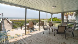 Una terrazza coperta all'aperto con sedie e un tavolo, con vista sulla spiaggia.