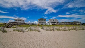 A beachfront property with multiple buildings, including a large house with a balcony and a smaller house with a porch.