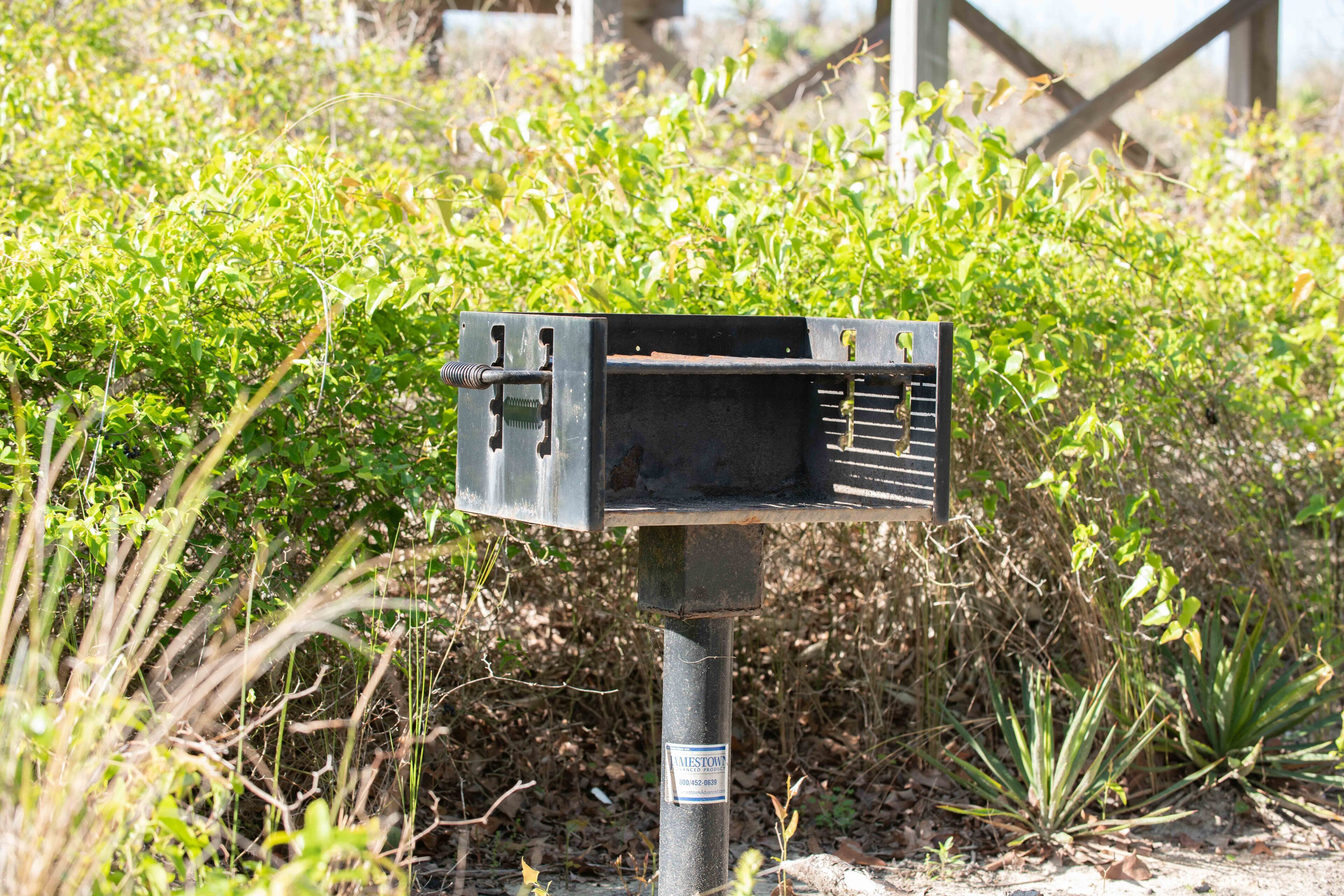 Un buzón de metal con una etiqueta en un poste, en un entorno natural.
