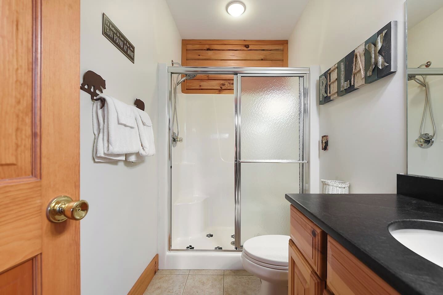 Une salle de bain avec une douche à parois de verre, des toilettes, un lavabo et des meubles en bois.