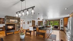 Une cuisine moderne dotée d’un îlot central, d’une cheminée et d’un coin repas avec des meubles en bois.