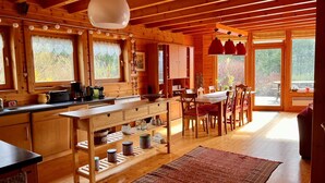 A wooden cabin interior with a kitchen, dining area, and large windows. - Nid de la Bergeronnette - The entire Chalet (Dabo)