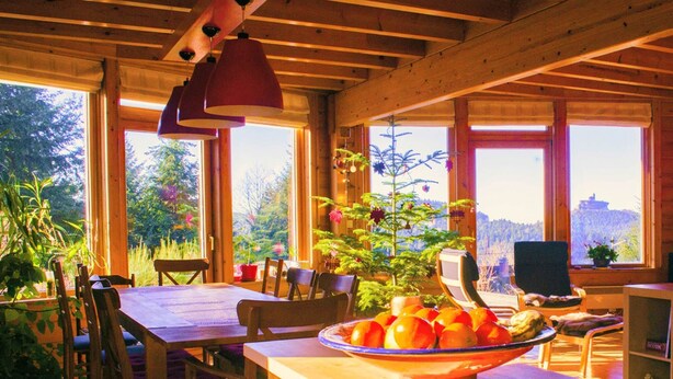 A wooden cabin interior with a dining table, chairs, a large window, and a bowl of fruit. - Nid de la Bergeronnette - The entire Chalet (Dabo)