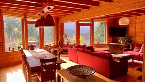 A cozy cabin interior with a dining area, a red sofa, and a television. - Nid de la Bergeronnette - The entire Chalet (Dabo)