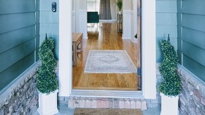 A house entrance with a wooden floor, a welcome mat, and two potted plants. - Manassas House 4 BDR  Patio Firepit (Tallahassee)