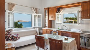 Een keuken met houten kastjes, een glazen tafel en uitzicht op zee.