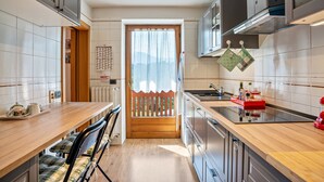 Una cocina moderna con encimera de madera, electrodomésticos de acero inoxidable y vistas a través de una puerta de madera.