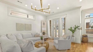 A modern living room with a white sofa set, a round coffee table, and a chandelier.