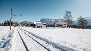 Een met sneeuw bedekte spoorlijn met huizen en bergen op de achtergrond.