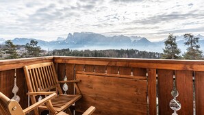 Eine Holzterrasse mit einem Holzstuhl und einem verzierten Metallkunstwerk.