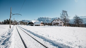 Eine verschneite Eisenbahnstrecke mit Häusern und Bergen im Hintergrund.