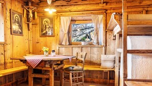 Un intérieur rustique en bois, avec une table en bois, des chaises, un banc et une fenêtre agrémentée de rideaux.