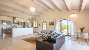 A spacious living area with a kitchen, a sofa, a coffee table, and a dining table.