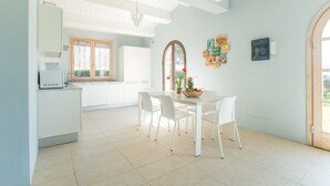 Una cocina moderna con armarios blancos, una mesa de comedor con sillas y una araña.