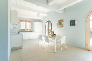 Una cocina moderna con armarios blancos, una mesa de comedor con sillas y una araña.