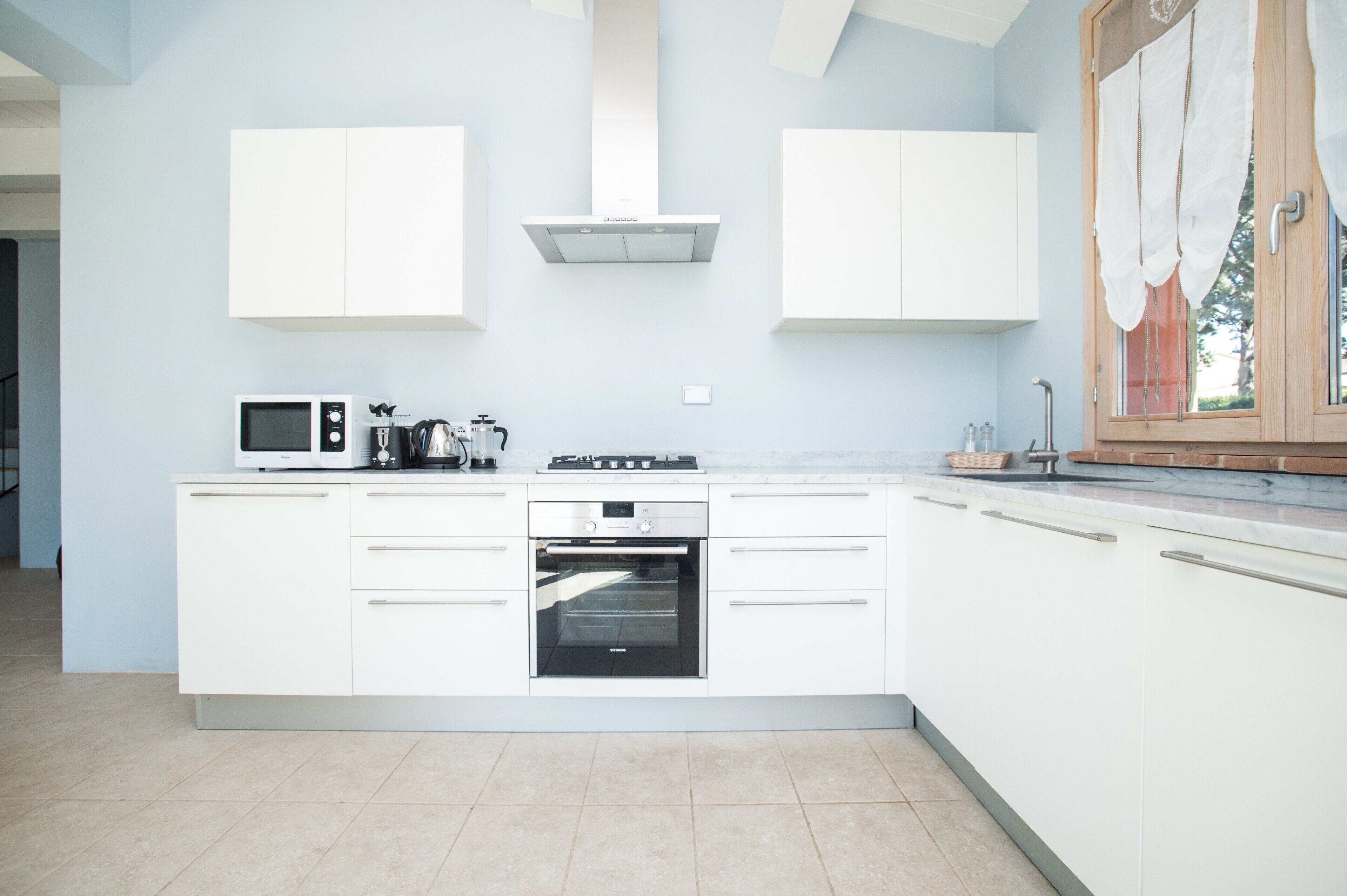 A modern kitchen with white cabinetry, a built-in oven, and a microwave.