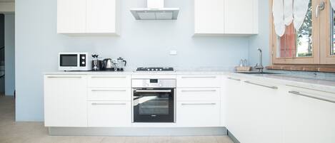 A modern kitchen with white cabinetry, a built-in oven, and a microwave.